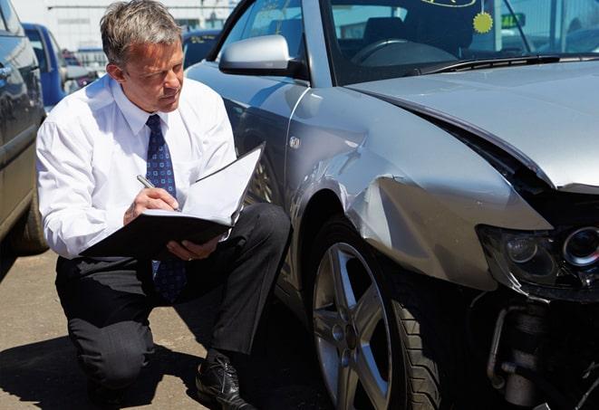 person holding auto insurance card with vehicle in background